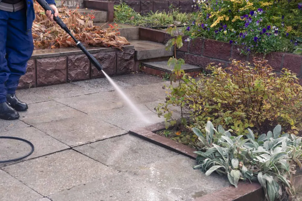 Pressure washing garden paving beside a planted border